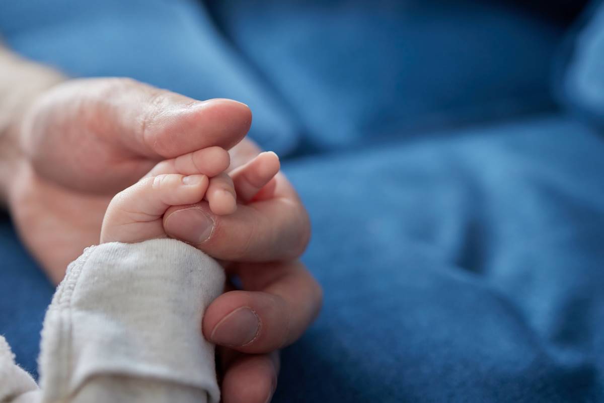 Une personne tenant la main d'un bébé. L'acte de naissance pour Français né en Tunisie peut se procurer en ligne.